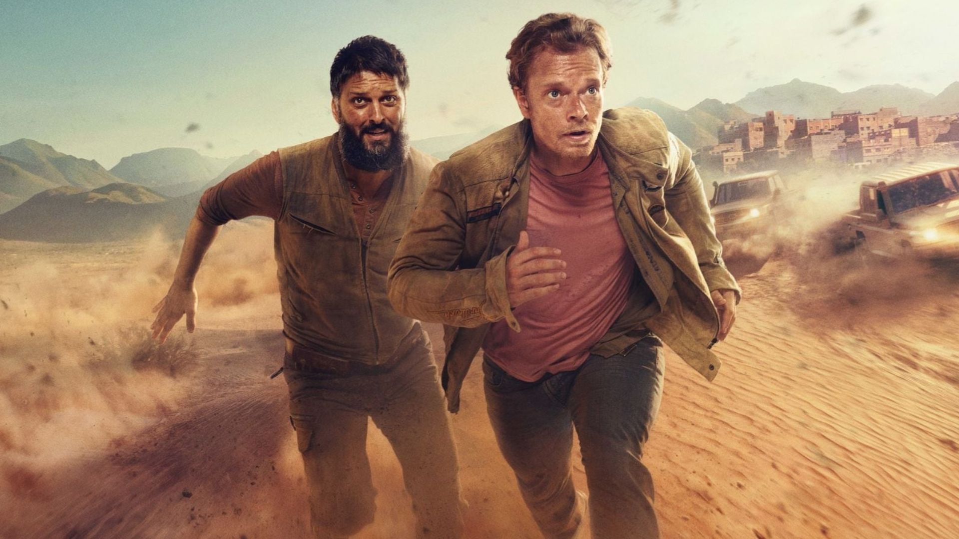 Aflie Allen and Shazad Latif run away from a group of cars in the desert