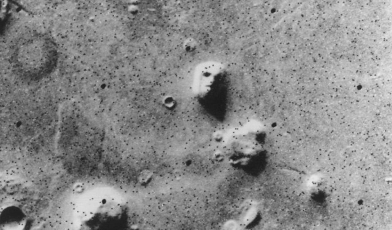 a black-and-white photograph of a rocky landscape, including one rock that looks vaguely like a human face due to shadows