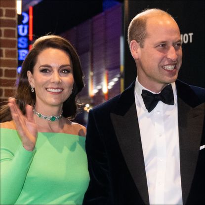 Kate Middleton waves while wearing a bright green dress and an emerald choker while husband Prince William wears a tuxedo