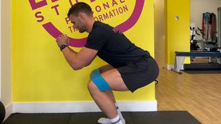 Sam Shaw demonstrates squatting with a resistance band