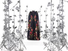 A floral cape surrounded by cameras, part of the Met Gala 2024 exhibition