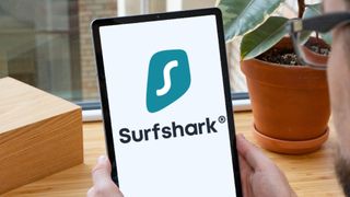 Två händer håller upp en surfplatta som kör Surfshark.