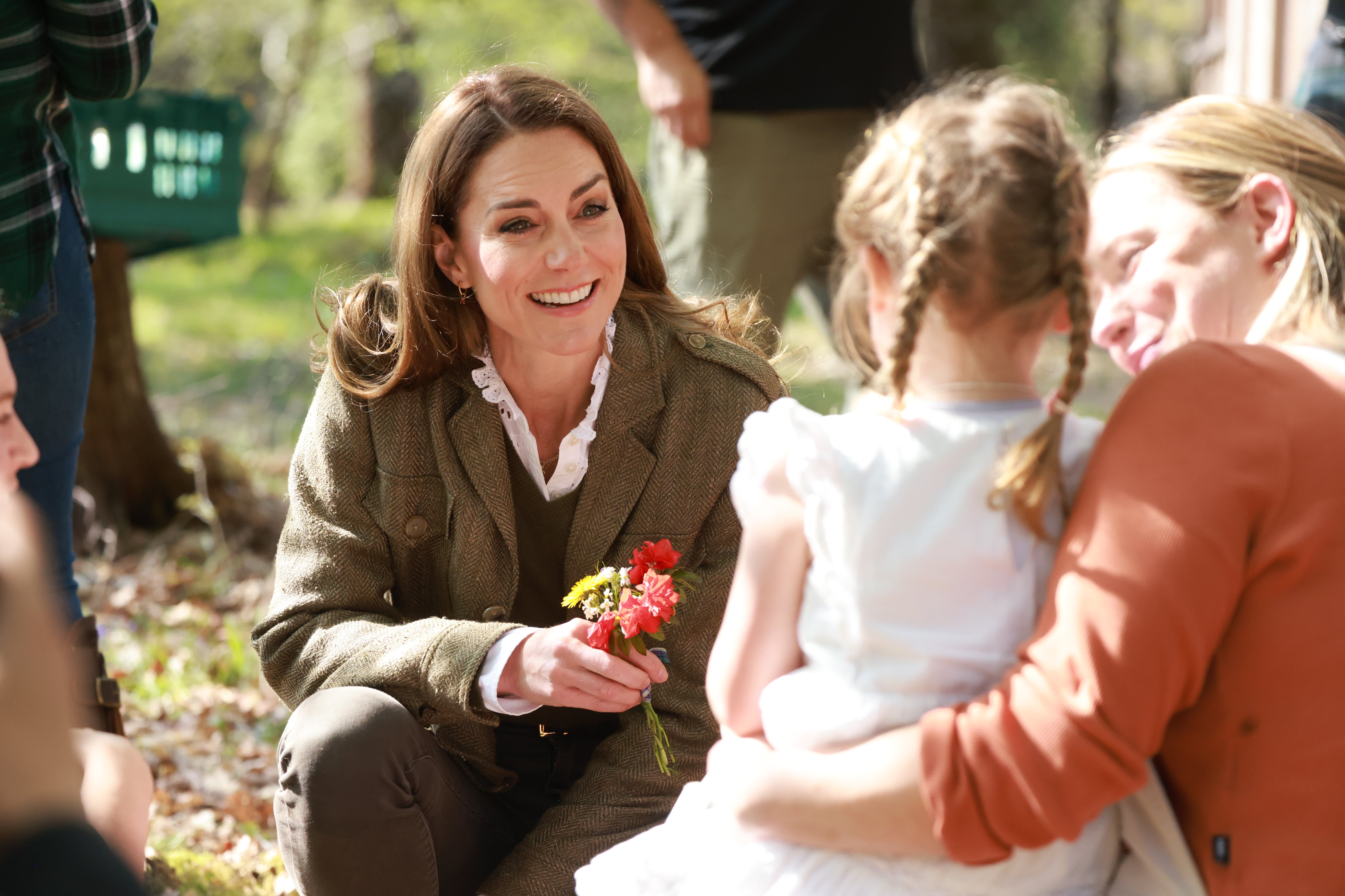 Kate Middleton kneeling down to talk to a little girl and mom in the woods