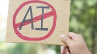 Close up hand holds paper card with No AI, prohibition sign
