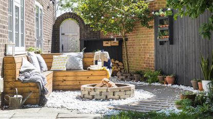 Back yard with bench seating a firepit and plenty of potted plants