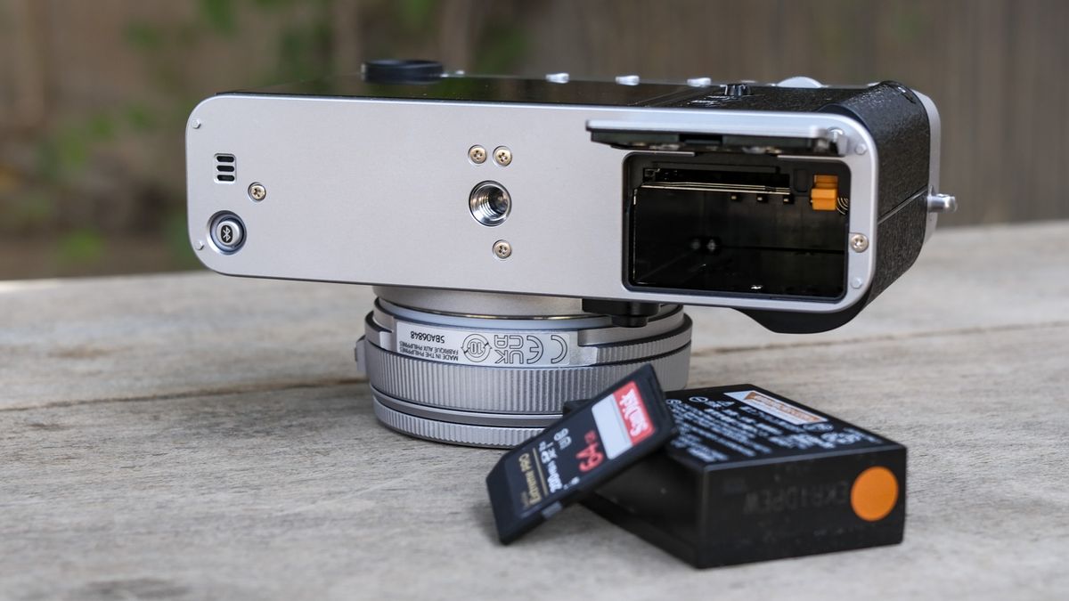 Underside of the Fujifilm X-E5 with its battery door open, battery and memory card removed