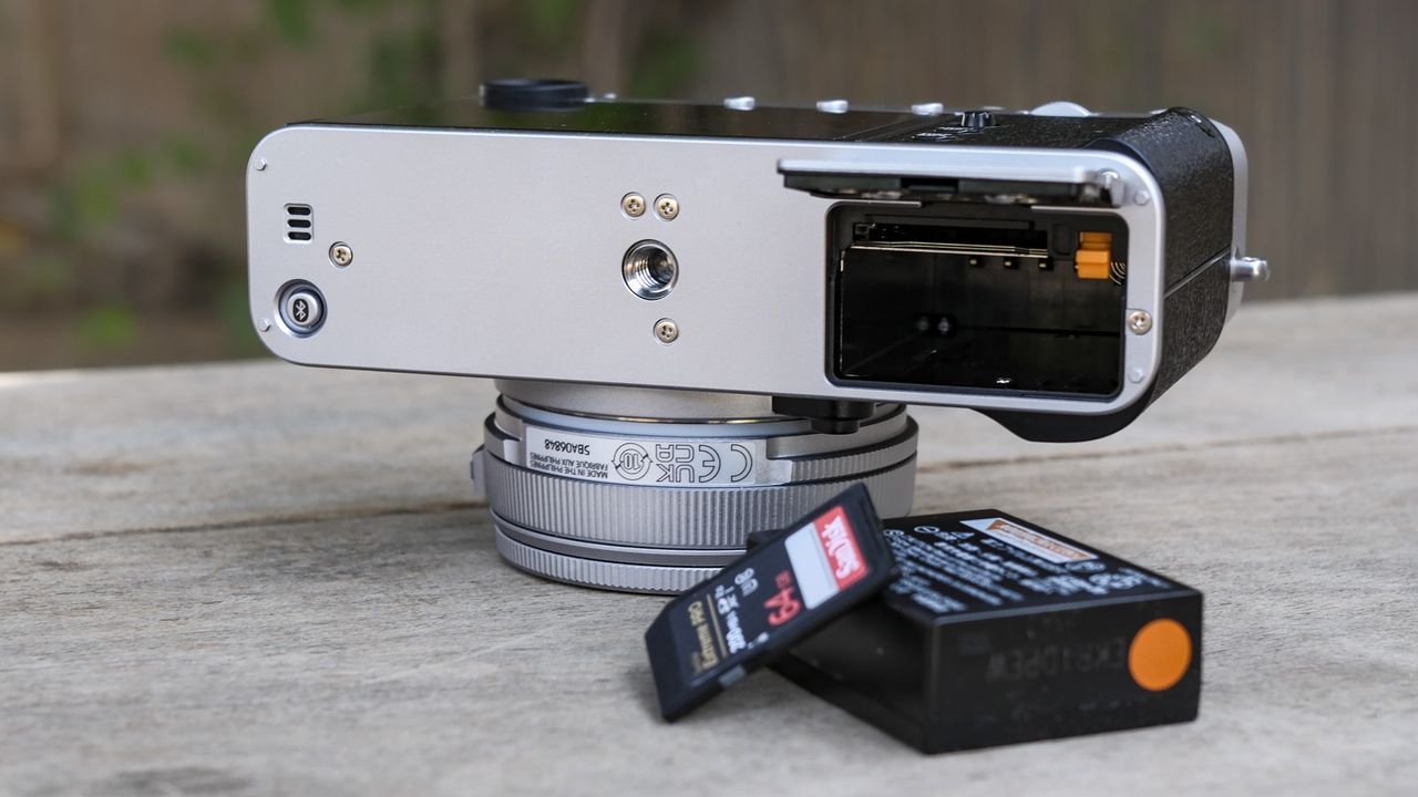 Underside of the Fujifilm X-E5 with its battery door open, battery and memory card removed