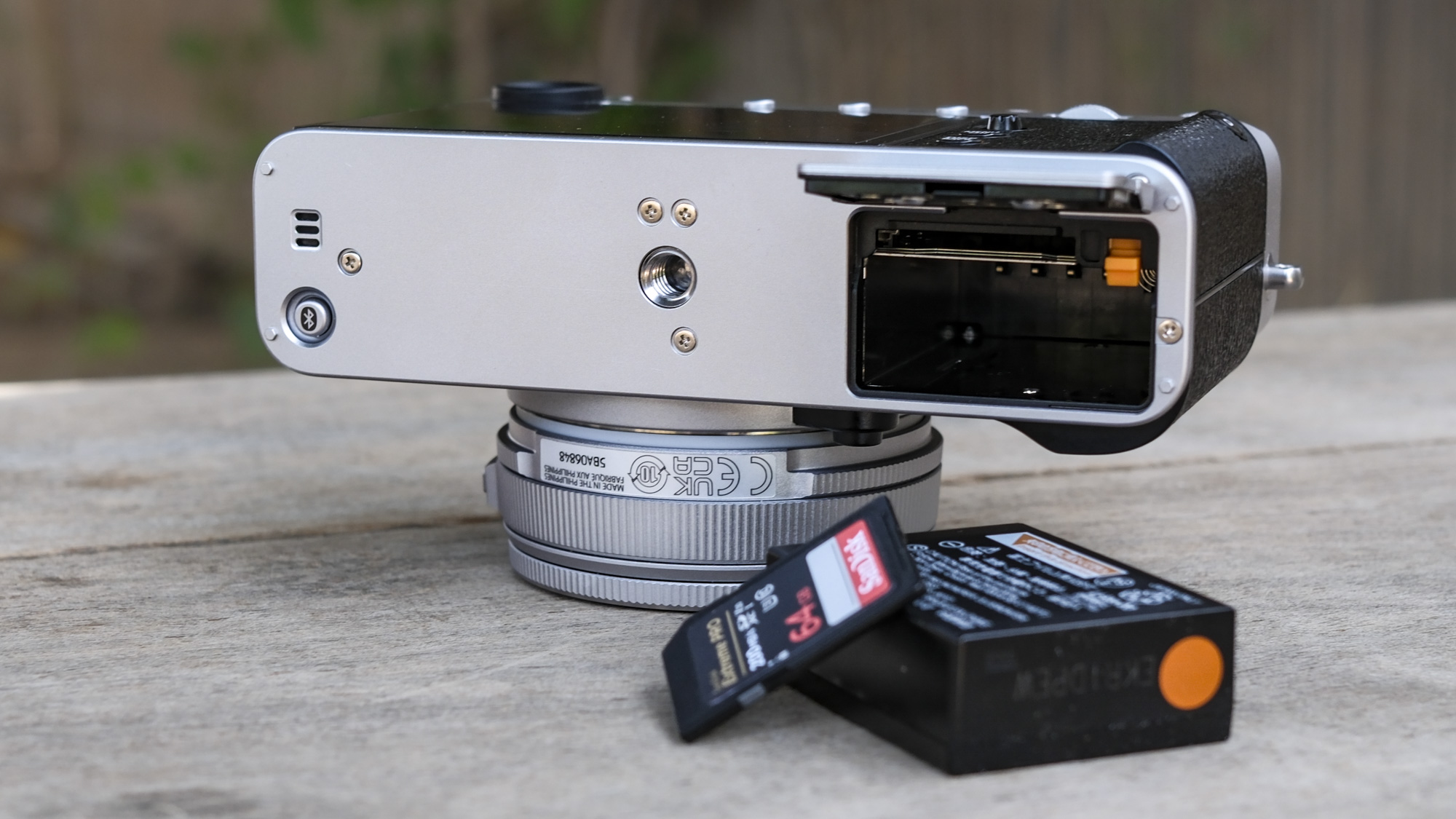 Underside of the Fujifilm X-E5 with its battery door open, battery and memory card removed