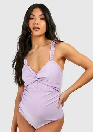 A pregnant model wearing a lilac maternity swimsuit from Boohoo. 