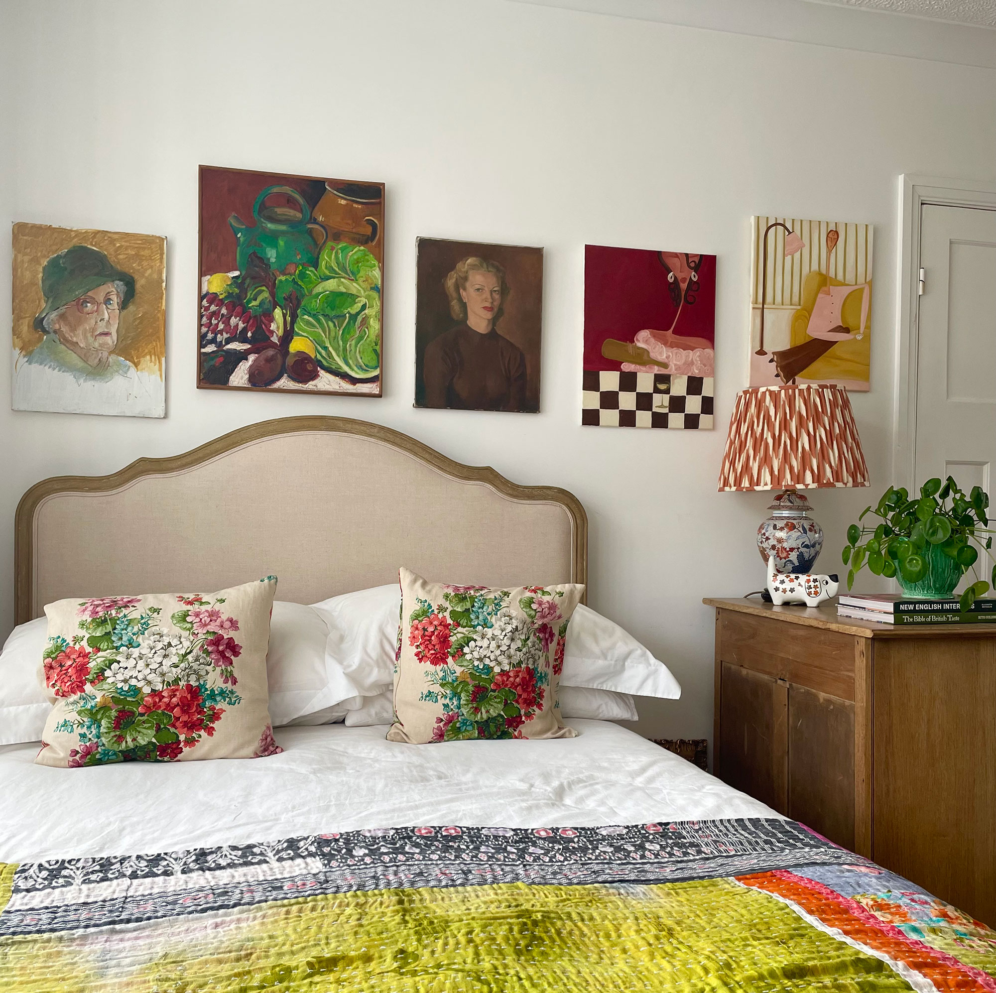 Row of artwork on wall behind bed