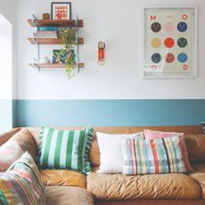 A living room with a corner brown leather sofa and a two-tone wall in blue and white