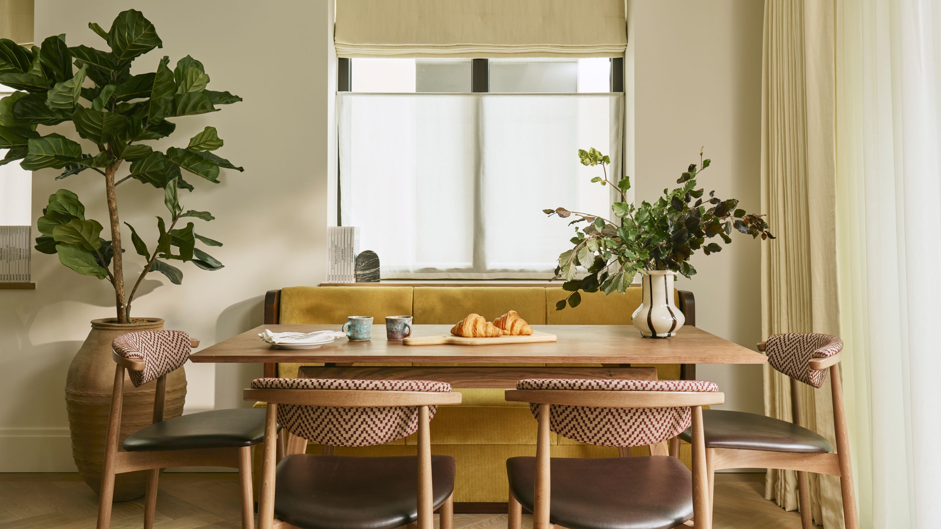 a warm neutral dining area with a yellow banquette and wooden table and chairs