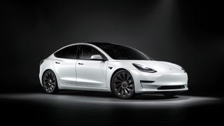 Une Telsa Model 3 blanche dans un studio avec un fond noir.