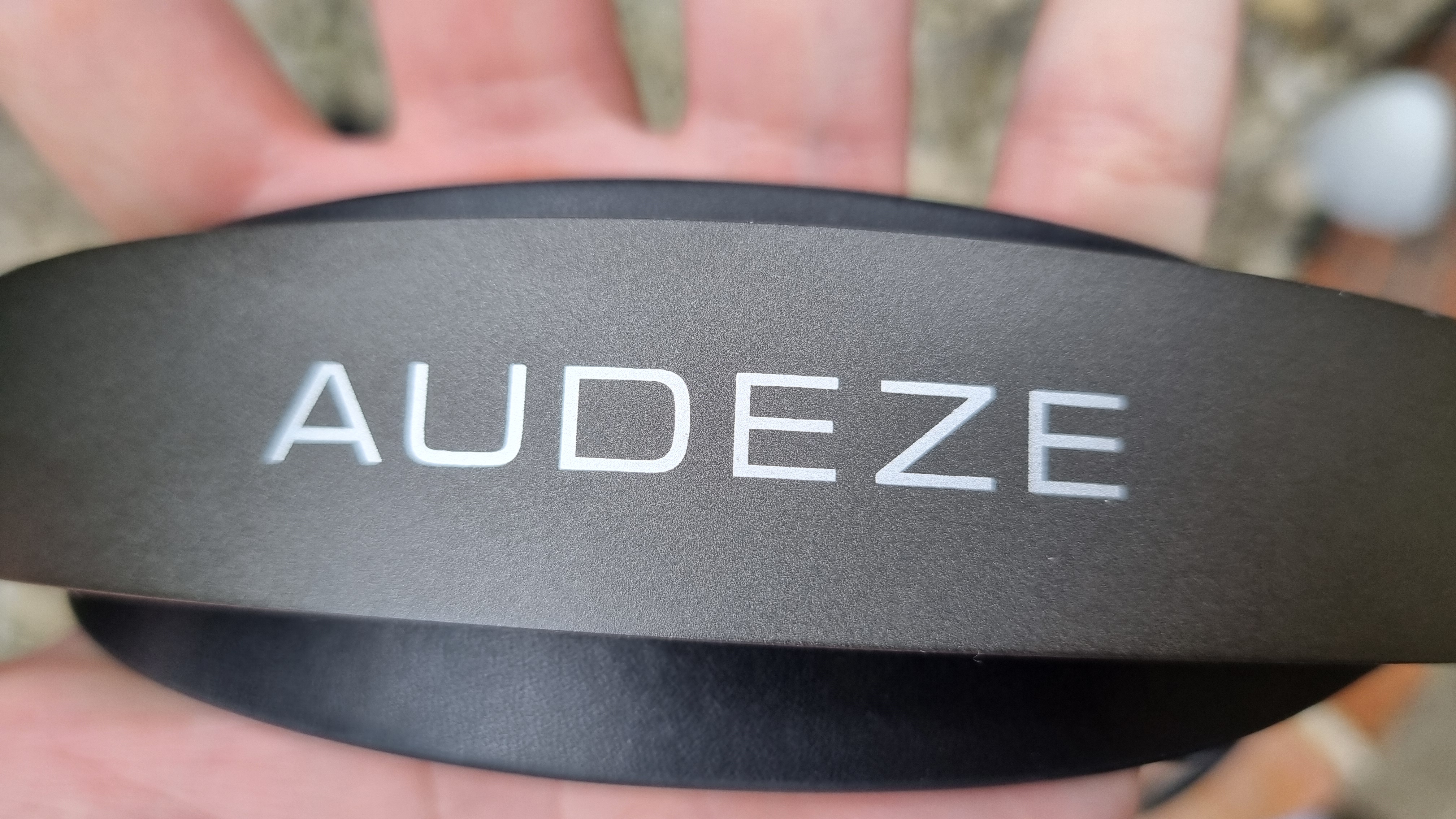 The top of the outer headband of the Audeze MM-100, showing the Audeze text in white font