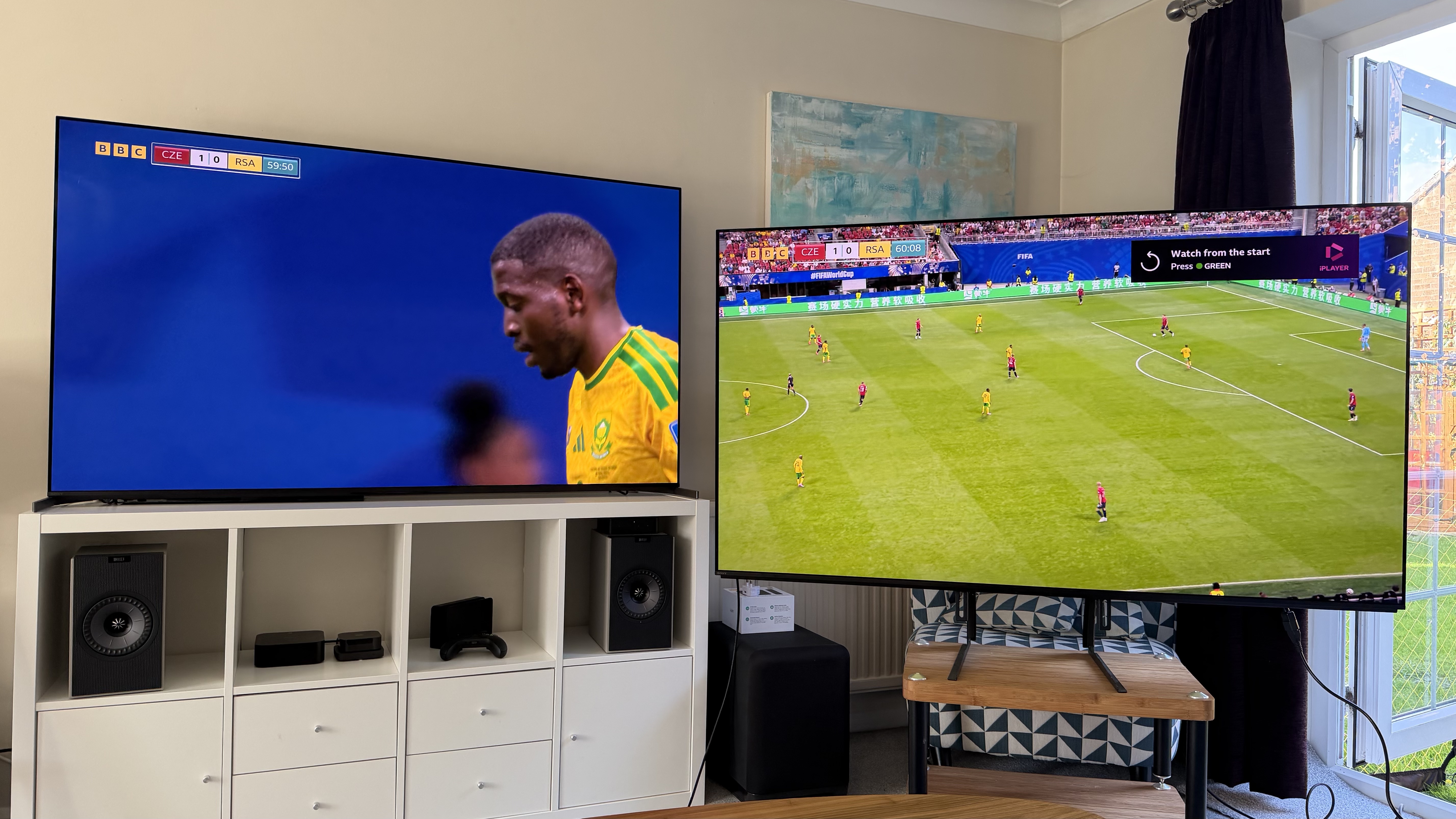 Two 65-inch TVs showing football, pictured in a living room