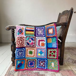 crochet blanket on a wooden armchair in a room 