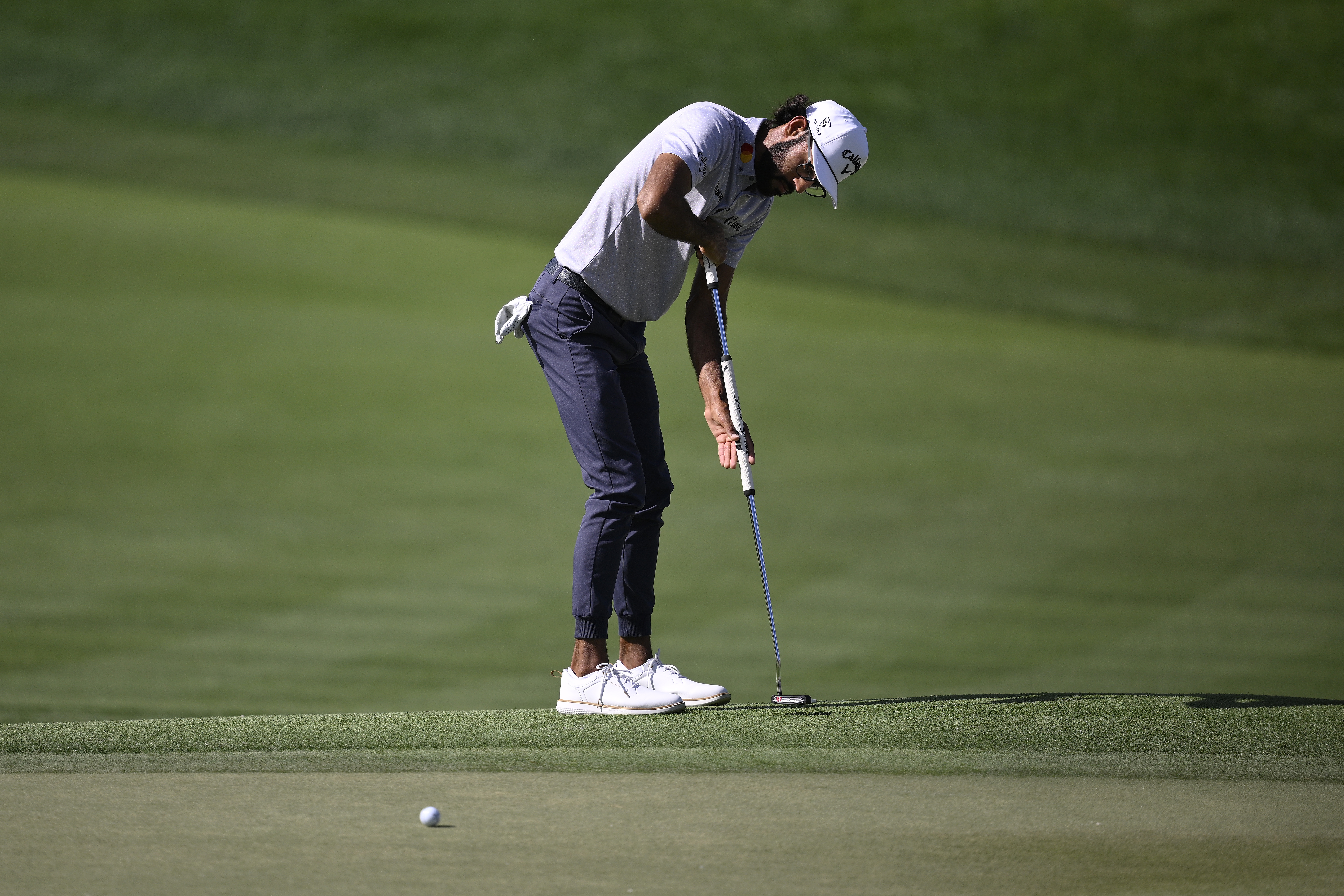 Akshay Bhatia hits a putter