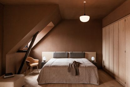 A terracotta/brown painted bedroom with gray bedding
