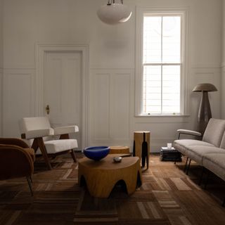 Living room with warm white walls, wood floor and wooden furniture with accents of white boucle