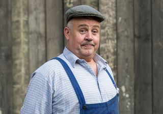 Fred Buckle in Call the Midwife wearing a flat cap and a check shirt 