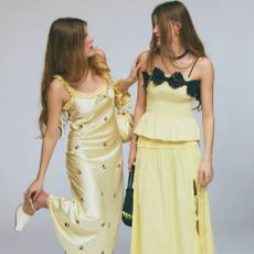 Two models wearing yellow dresses from Damson Madder.