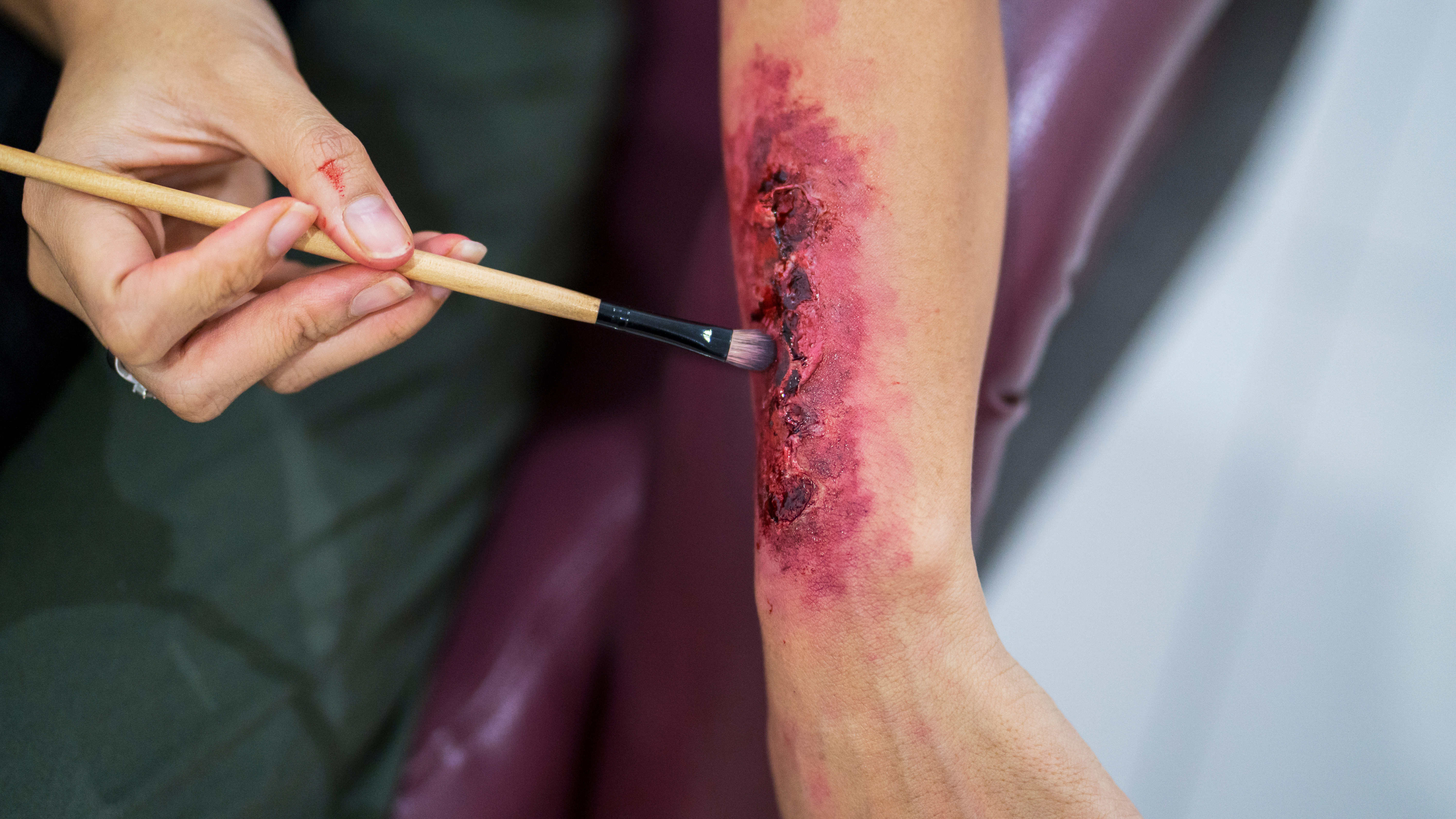 A fake wound being painted onto an arm