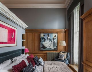 Architectural bedroom with wooden panelling and dark grey walls, accent chair and grey curtains