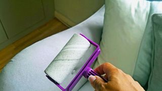 A lint roller being used to clean furniture