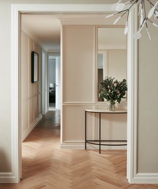 Neutral walls in a hallway with wooden floors and luxe brass homewares
