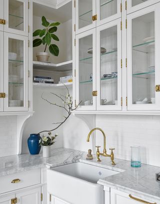 a white kitchen with a brass faucet