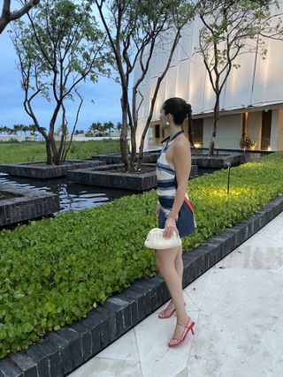 senior editor Anna LaPlaca wearing a blue striped SIR dress and red The Row sandals at the St. Regis Kanai Riviera Maya