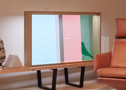Vitrine television, by Vitra, Panasonic and Daniel Rybakken, on a wooden stand next to a brown leather chair