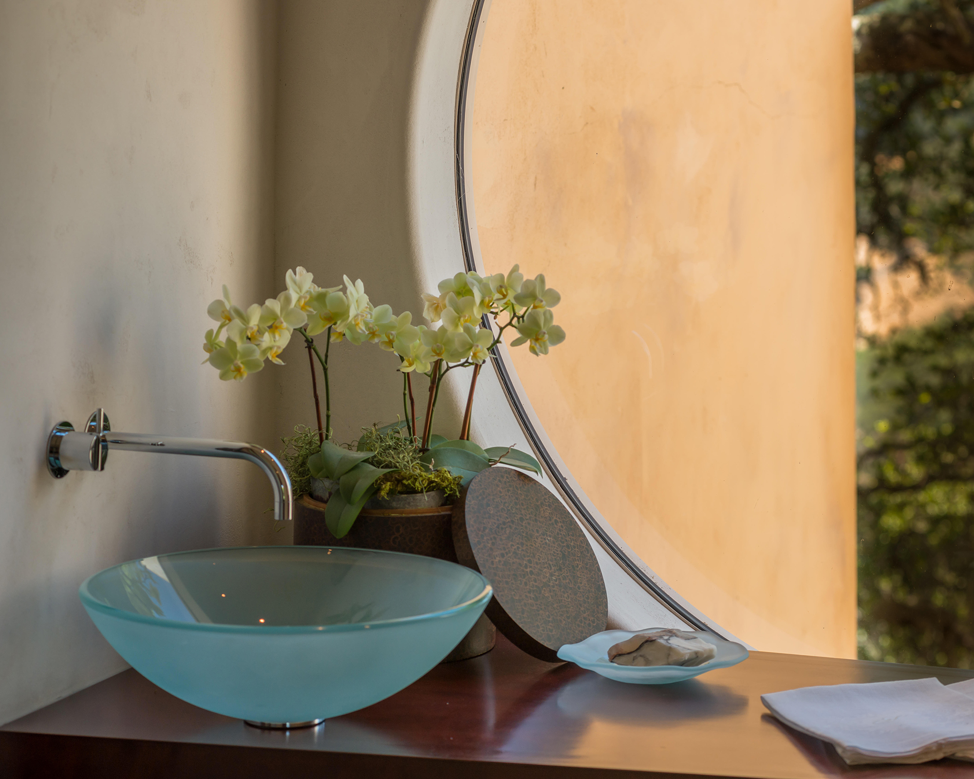 Potted orchid plant in a bathroom by the sink and window