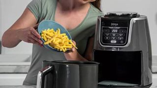 Woman putting chips in a Ninja AF160UK Max Air Fryer