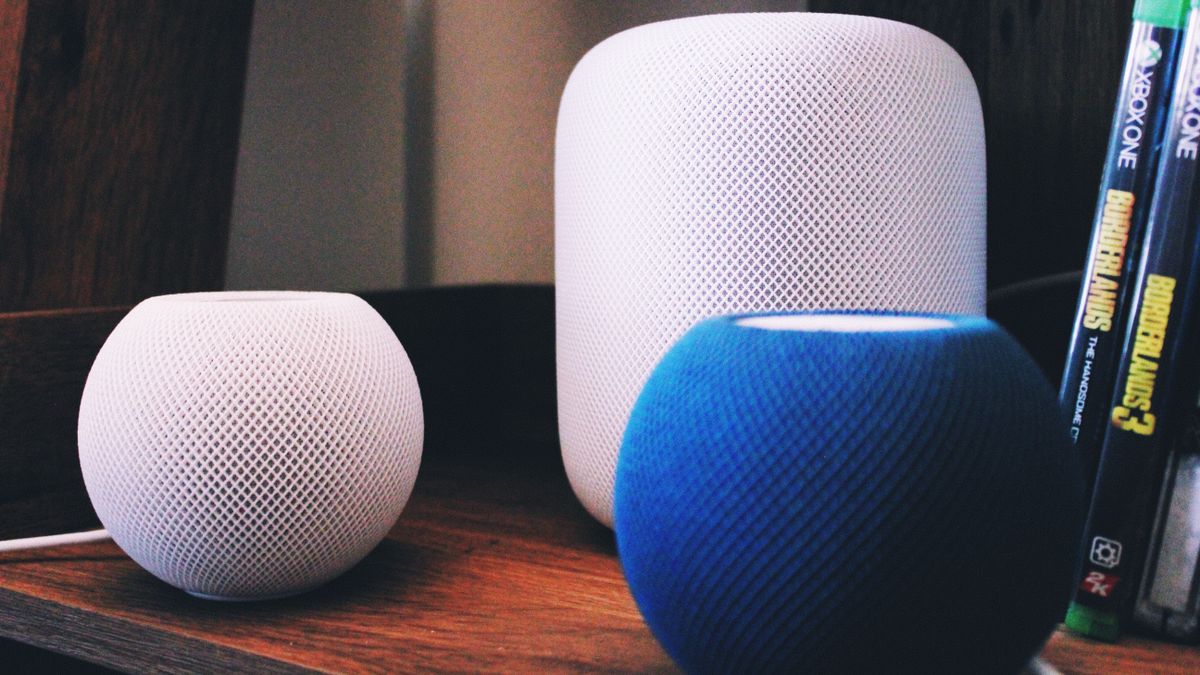 A white Homepod alongside two homepod minis, one white one blue