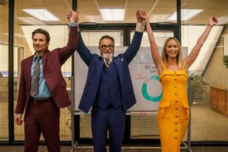 Chris Evans, Andy Garcia and Emily Blunt holding hands in a boardroom in Pain Hustlers