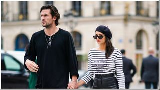 Nina Dobrev and Grant Mellon walk hand in hand - Nina Dobrev wears a beret hat, a black and white striped top with a printed sentence "why have there been no great women artists ?", a black leather skirt, sunglasses, outside Guy Laroche, during Paris Fashion Week - Womenswear Spring Summer 2020 on September 25, 2019 in Paris, France.