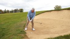 Club strikes grass face of bunker on backswing