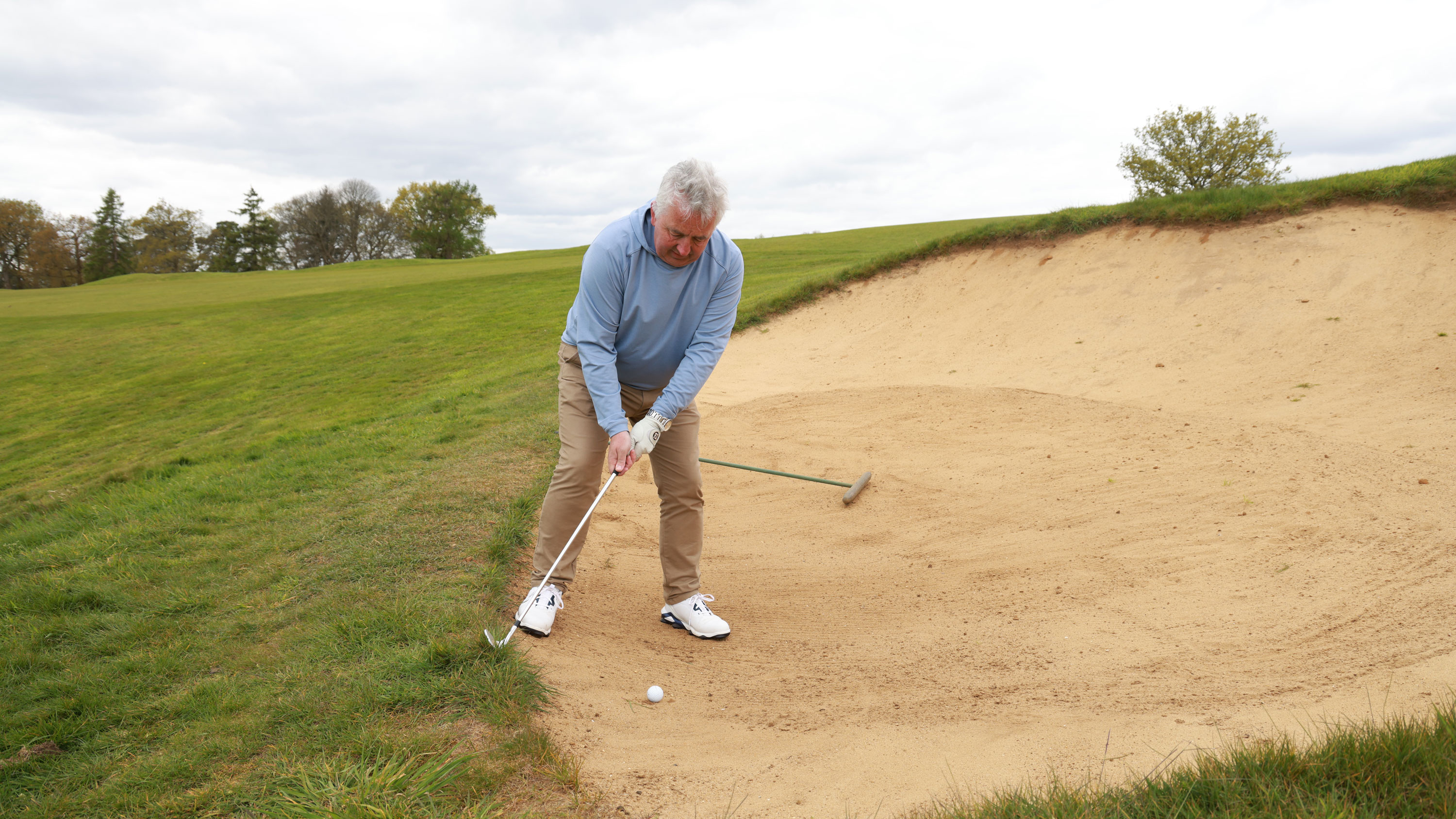 Club strikes grass face of bunker on backswing