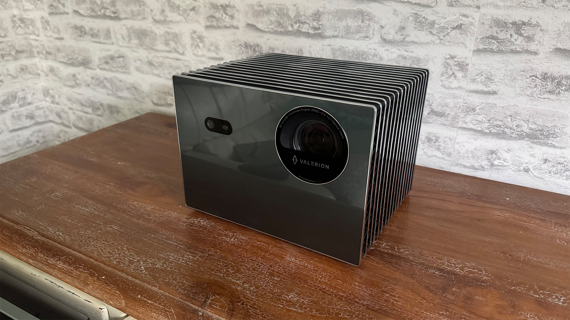 Valerion VisionMaster Pro 2 home cinema projector on wooden sideboard in front of white brick wall