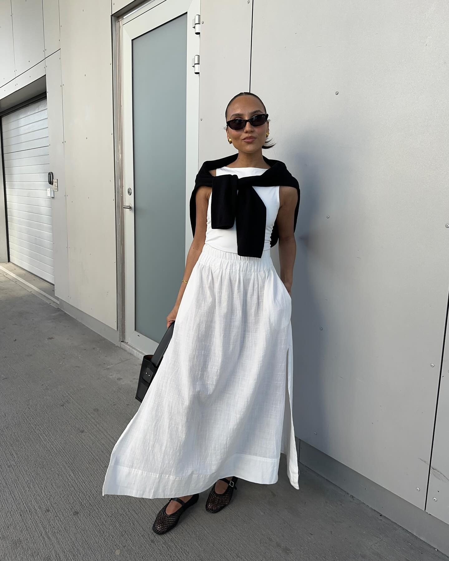 French woman wearing white maxi skirt, white tank top, black ballet shoes and black sweater.