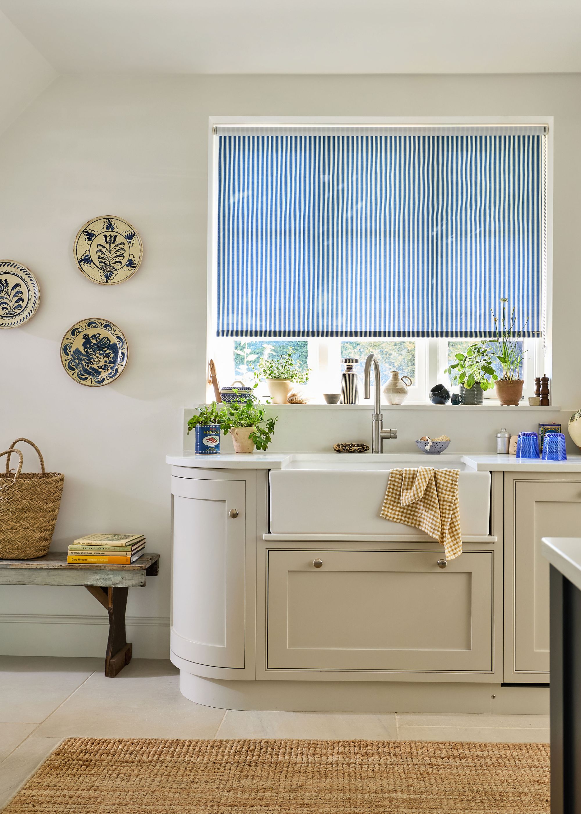 neutral kitchen with white walls and window with blue striped roller blind