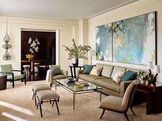 living room with neutral walls and big artwork with taupe sofas and glass coffee table view to dining room