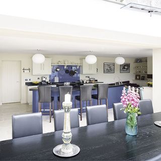 dining area near kitchen with long black table and leather chairs