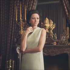 a woman (naomi watts as babe paley) stands in front of an ornate fireplace and candelabras