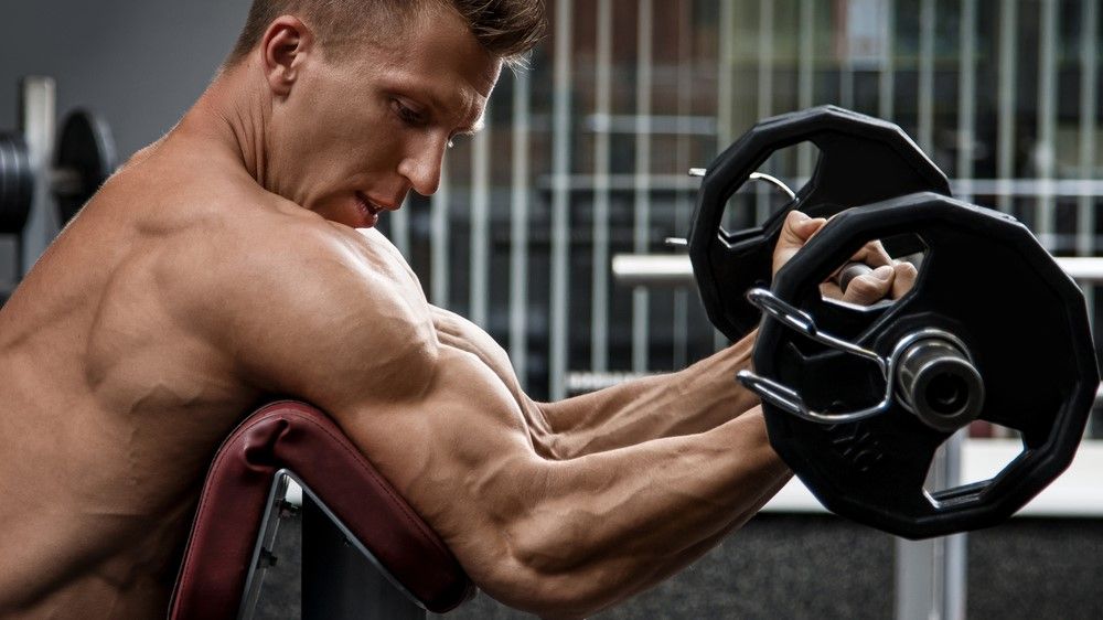 a photo of a man doing a preacher curl