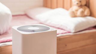 an air purifier in a room in front of a bed