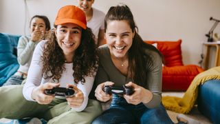 Young female friends enjoying video game at home - stock photo