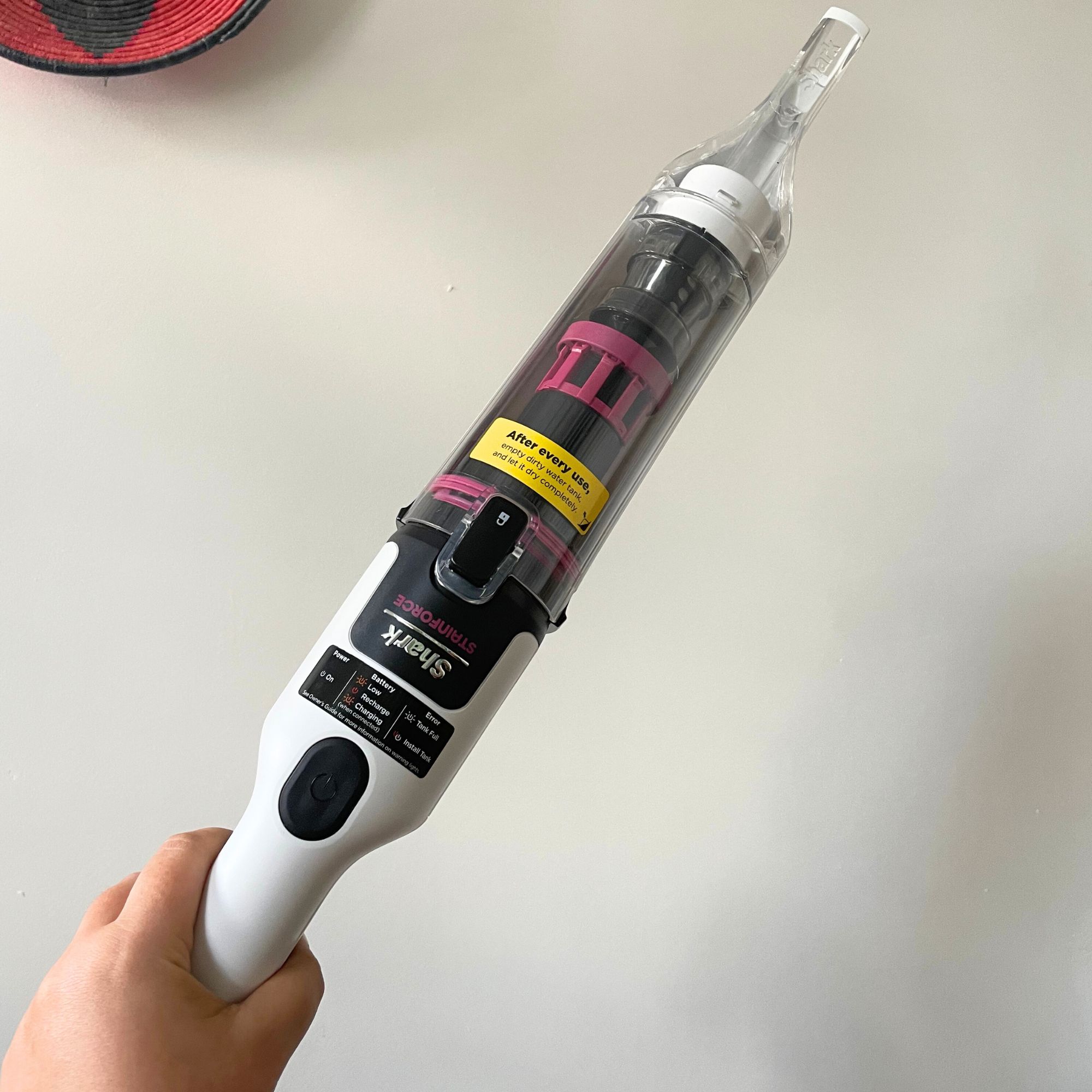 Hand holding the Shark Stainforce Spot Cleaner in front of a white wall