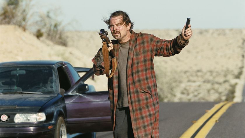 Leonardo DiCaprio as Bob holding a gun and a device in One Battle After Another